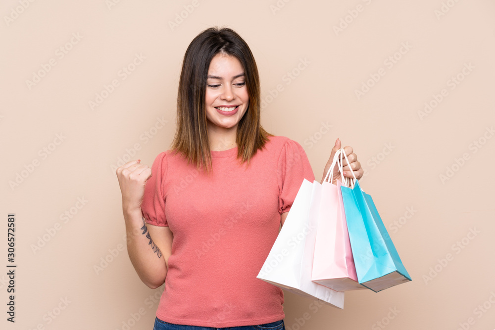 Young woman with shopping bag over isolated background celebrating a victory Young woman with shopping bag over isolated background celebrating a victory