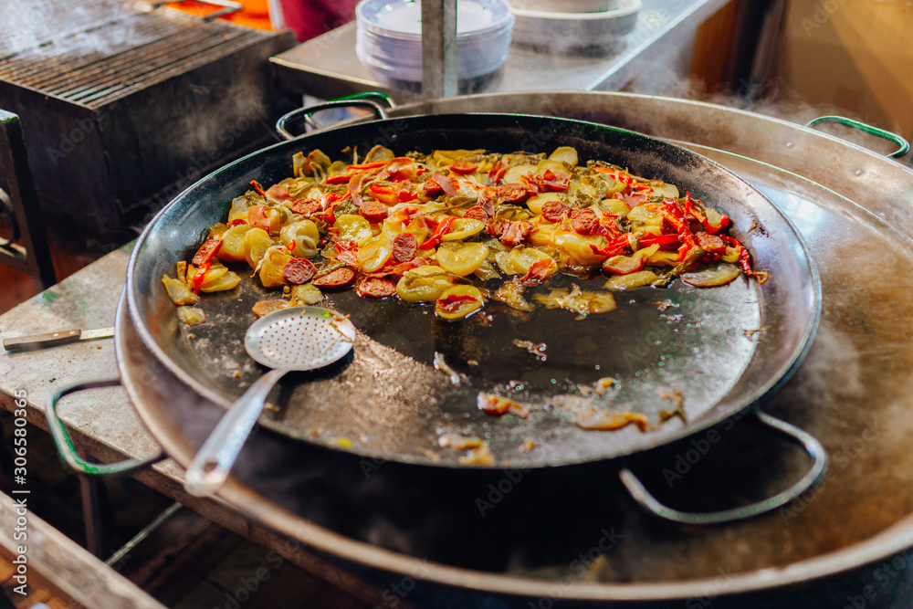 Fried potatoes with vegetables and sausages in a saucepan, cut into slices and fried in oil, in rustic style. Roasted Potato and Sausage in frying pan. Spanish food concept. Fried potatoes with vegetables and sausages in a saucepan, cut into slices and fried in oil, in rustic style. Roasted Potato and Sausage in frying pan. Spanish food concept.