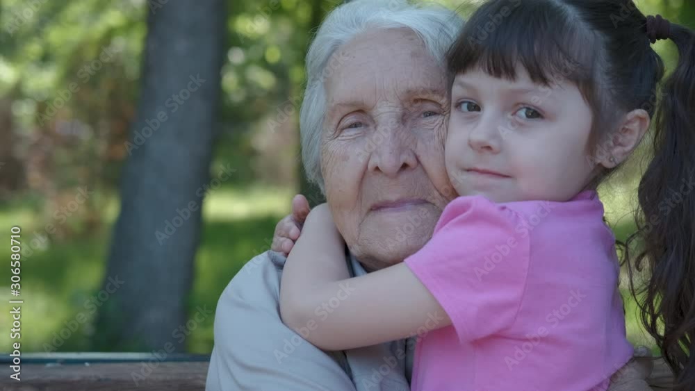 Hugging a grandmother. Cute little girl hugs her grandmother outdoors. Hugging a grandmother. Cute little girl hugs her grandmother outdoors.
