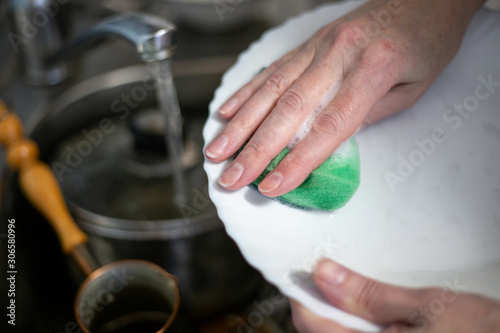 a woman washes dishes with a foam sponge