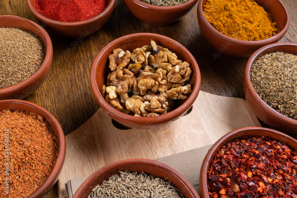 A selection of various colorful spices on a wooden table in bowls