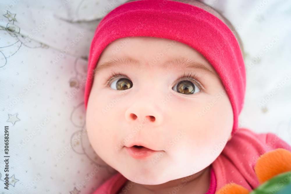 Beautiful portrait of 5 week old baby girl lying in a crib looking up towards camera. Baby care concept Beautiful portrait of 5 week old baby girl lying in a crib looking up towards camera. Baby care concept