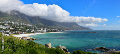 Panorama view Camps Bay beach and the 12 apostles mountain chain partly shrouded in long white clouds, Table Mountain, Cape Town, South Africa