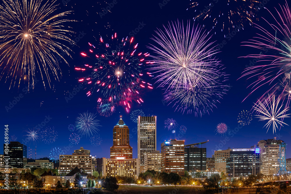 Fototapeta premium Straight view on Portland's downtown buildings and skyscrapers during night beautiful dark blue sky with flashing fireworks celebrating New Years Eve