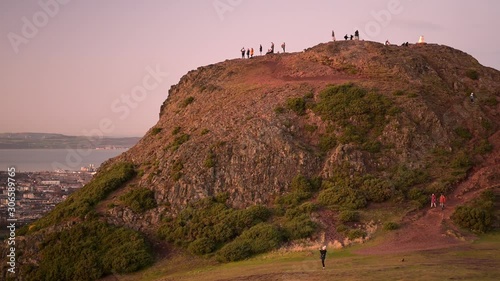 People climbing on top of the Holyrood park Arthur's seat mountain for a sunset time to take a view over the city of Edinburgh in Scotland