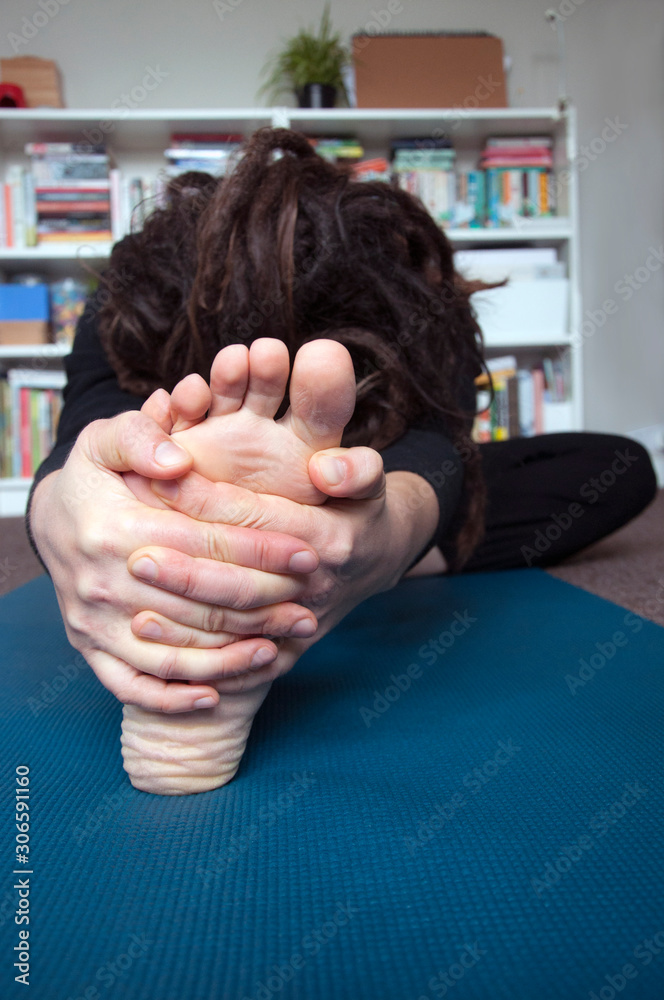 A woman practicing yoga in the comfort of her home. Head to knee forward bend / Janu Sirsasana