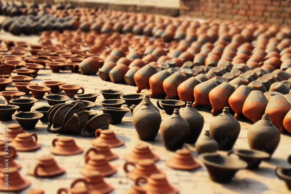 Obraz premium BHAKTAPUR, NEPAL - APRIL 22, 2014: Traditional clay pots and utensils are sold on the street of Bhaktapur city destroyed by an earthquake. Clay ceramics, production. UNESCO World Heritage.