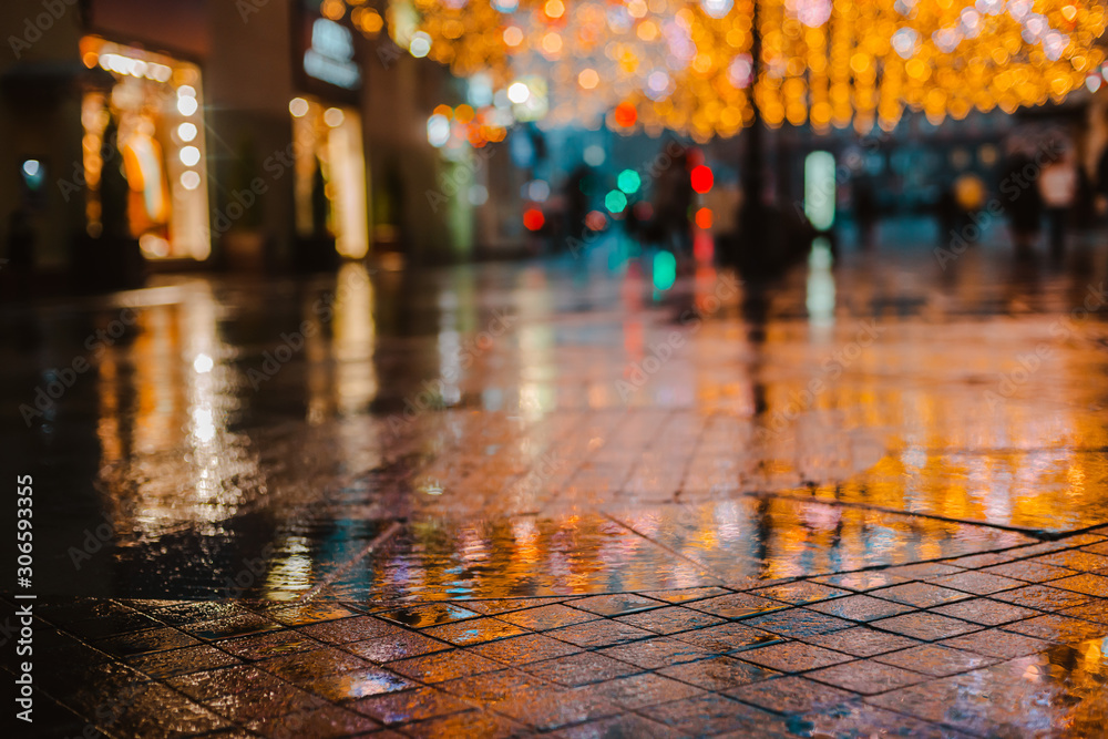 Rainy night in a big city, reflections of lights on the wet road surface.