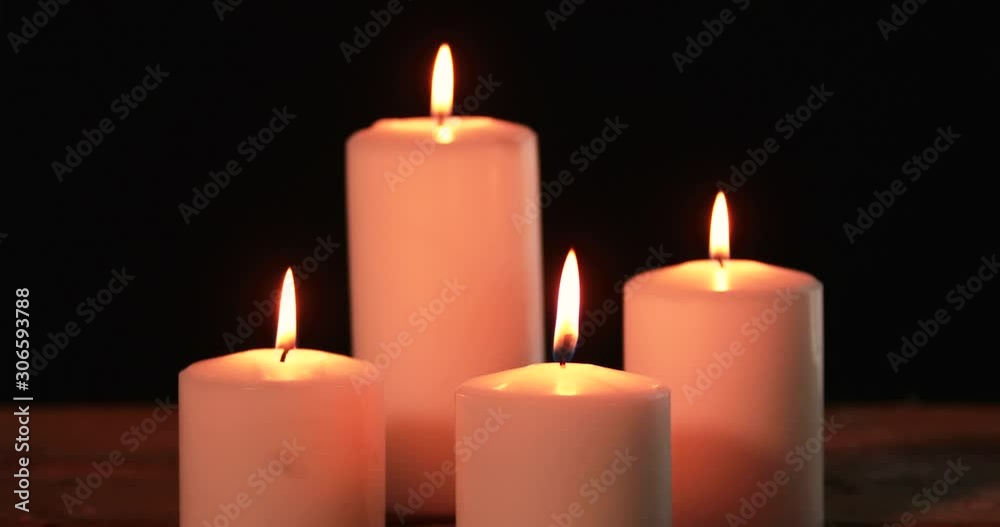 Four white Christmas candles illuminating on the dark background with bright light. Shot in 4k resolution Four white Christmas candles illuminating on the dark background with bright light. Shot in 4k resolution