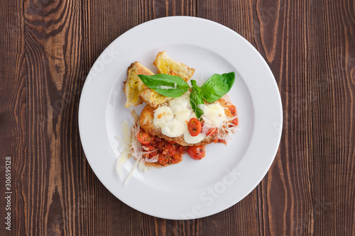 Top view of roasted chicken fillet with tomato cherry, parmesan and crouton on dark wooden background