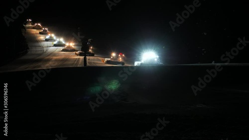 Snow Grooming Snowcat Machines Fix Trail on Ski Resort Slope at Night