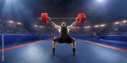 Tableau sur toile Male athlete squats with a barbell on a professional stadium