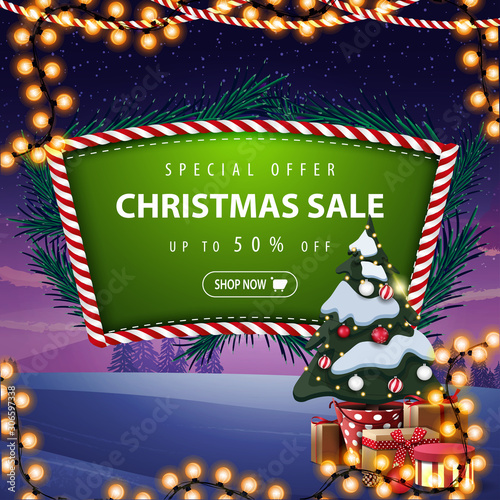 Special offer, Christmas sale, up to 50% off, green discount banner with Christmas tree branches, garland, winter landscape on the background and Christmas tree in a pot with gifts