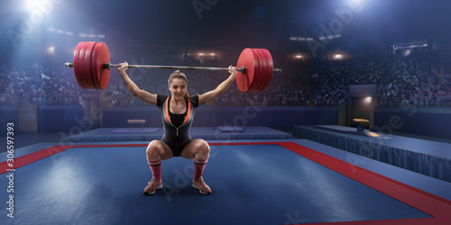 Female athlete squats with a barbell on a professional stadium. Stadium and crowd are made in 3d. photo