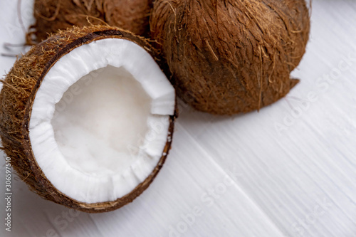 Half chopped coconut on a white wooden background. Tropical background with place for copy space. View from above