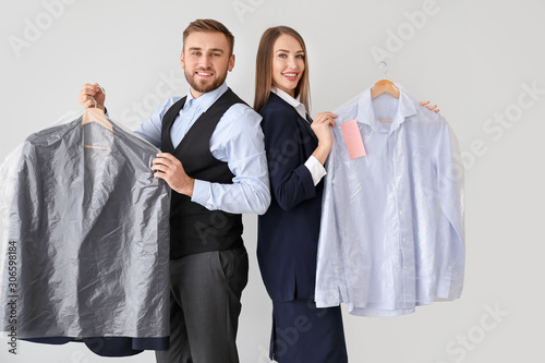 Workers of modern dry-cleaner's with clothes on light background