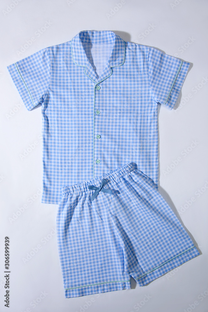 Baby pajamas. Sleeping outfit for baby girl. Pajamas in blue and white colors, square pattern. On white background, close-up shot and top view Baby pajamas. Sleeping outfit for baby girl. Pajamas in blue and white colors, square pattern. On white background, close-up shot and top view