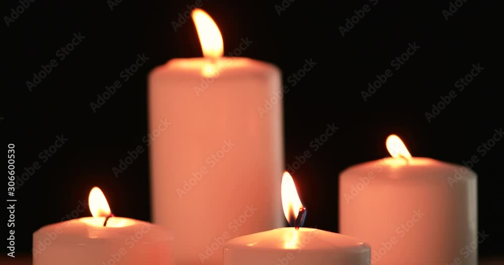 Close up of white Christmas candles burning on the dark background with bright light. Shot in 4k resolution Close up of white Christmas candles burning on the dark background with bright light. Shot in 4k resolution