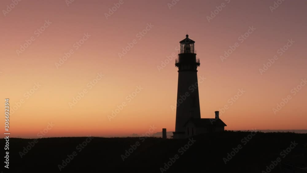 Silhouette of the Yaquina Head Lighthouse at dusk just after sunset standing dark against a pink evening sky. Silhouette of the Yaquina Head Lighthouse at dusk just after sunset standing dark against a pink evening sky.
