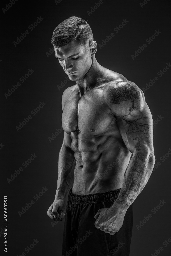 Fototapeta premium Very brawny guy bodybuilder posing. Beautiful sporty guy male power. Fitness muscled man in studio. Dark background.