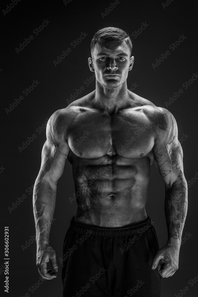 Very brawny guy bodybuilder posing. Beautiful sporty guy male power. Fitness muscled man in studio. Dark background.