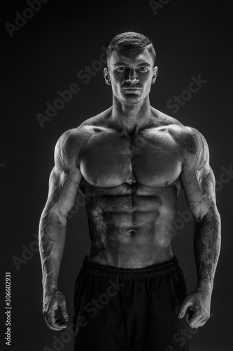 Very brawny guy bodybuilder posing. Beautiful sporty guy male power. Fitness muscled man in studio. Dark background.
