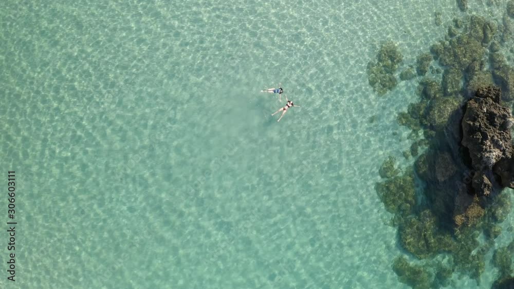 Two Beautiful young woman swimming, lying on a water surface in crystal clear ocean Two Beautiful young woman swimming, lying on a water surface in crystal clear ocean