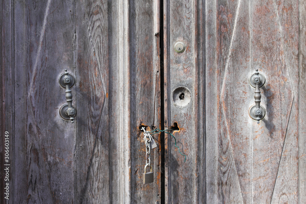 Two closed padlocks with a chain on an old wooden door Two closed padlocks with a chain on an old wooden door