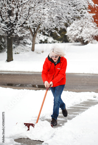 Young man with snow shovel cleans sidewalks in winter. Canada