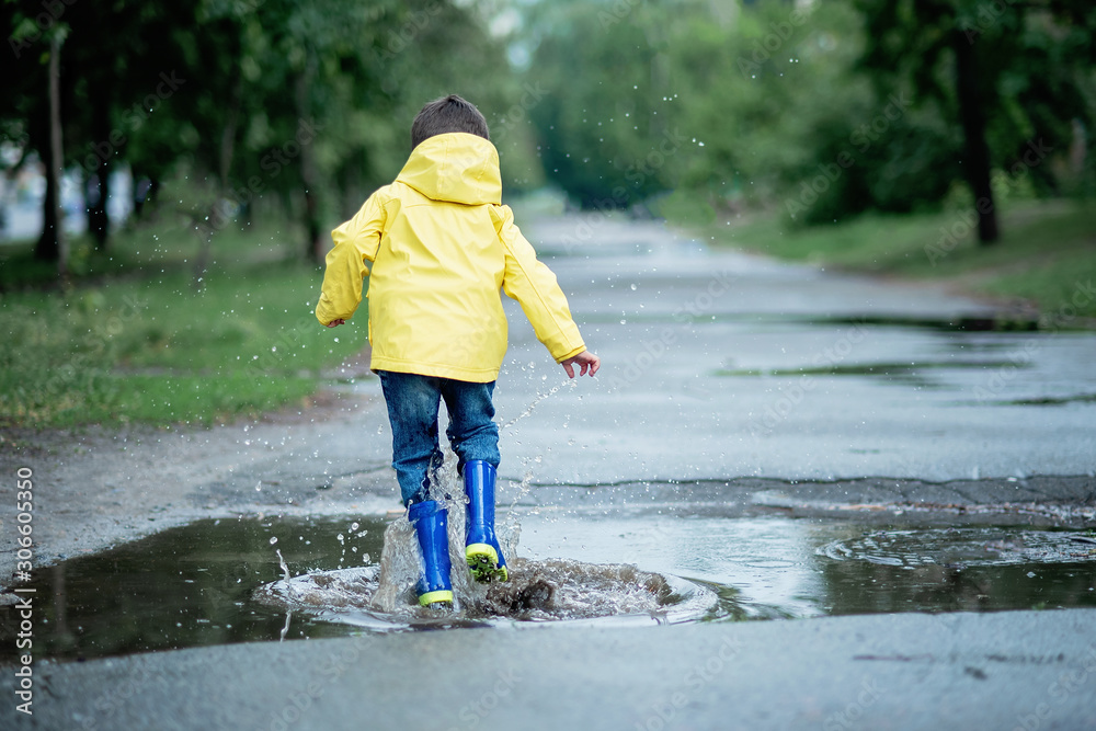 A wet child is jumping in a puddle. Fun on the street. Tempering in summer A wet child is jumping in a puddle. Fun on the street. Tempering in summer