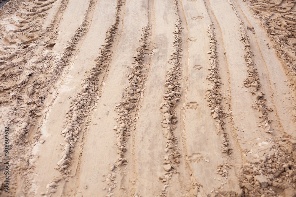 Naklejka premium Sand texture at a construction site. Traces of wheels.