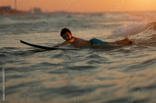 Surfer in action. A boy trains on the waves at sunset or sunrise photo