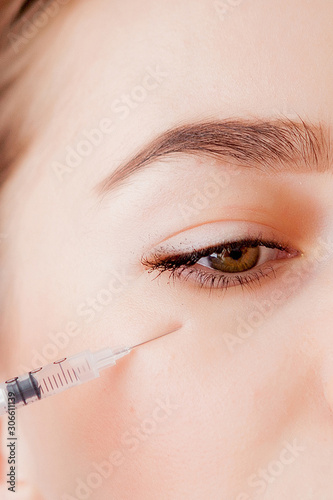 The doctor cosmetologist makes the Botulinotoxin injection procedure for tightening and smoothing wrinkles on the face skin of a beautiful, young woman in a beauty salon.Cosmetology skin care