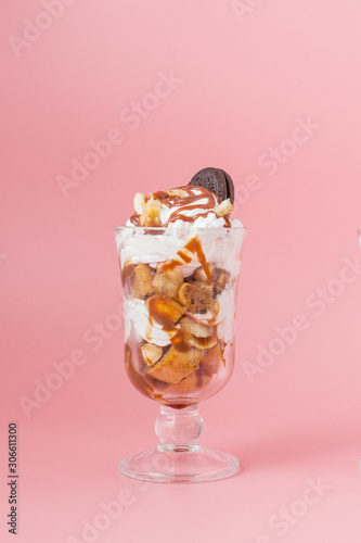 Sweet dessert in glass with biscuit and whipped cream on pink bsckground, selective focus and blank space