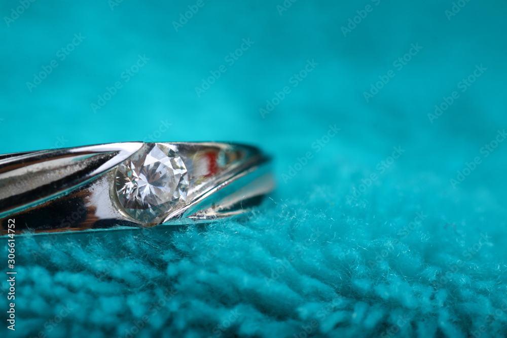 Close up shoot of an white gold engagement ring with diamonds on an isolated green background