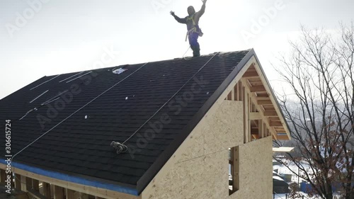Wallpaper Mural Aerial zooming in view of smiling tiler standing on the roof top of residential house under constuction. Bright blue sky is on the background Torontodigital.ca