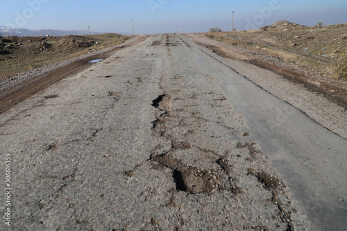 road in desert. Potholes in the pavement on a rural road. Poor  road concept