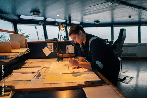 Marine navigational officer during navigational watch on Bridge . He does chart correction of nautical maps and publications. Work at sea photo