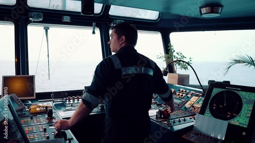 Marine navigational officer during navigational watch on Bridge . He is maneuvering the ship. Work at sea. photo