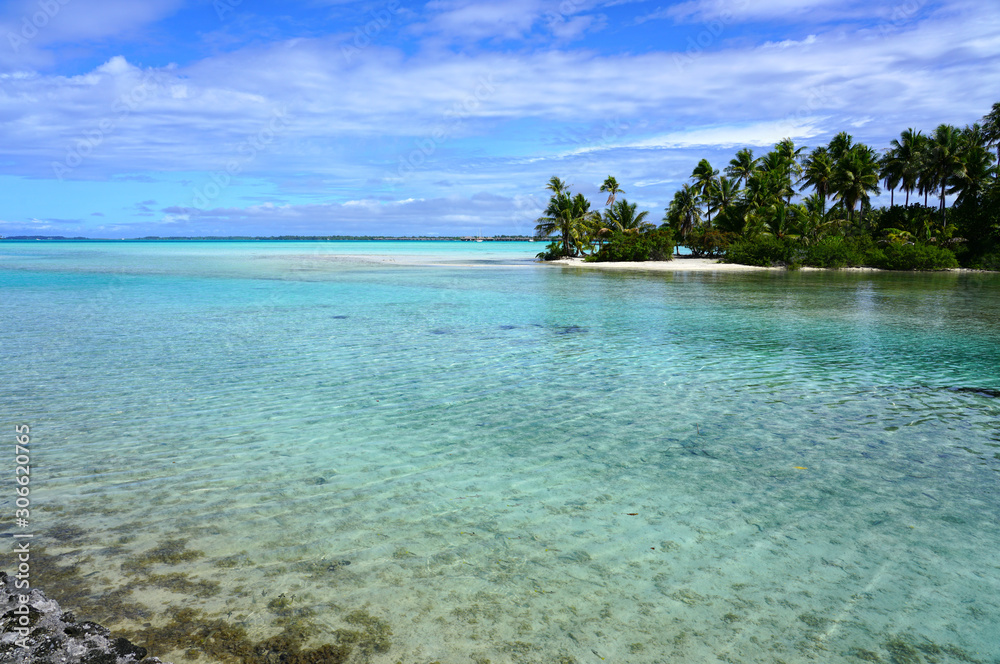 View of a tropical landscape with palm trees, white sand and the turquoise lagoon water in Bora Bora, French Polynesia, South Pacific