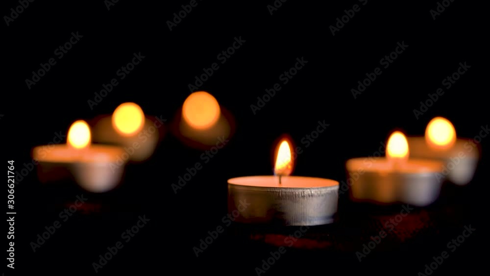Decorative small candles burn on a dark background. Small candles. Close-up shot. Lots of candles with shallow depth. Rest and peace Decorative small candles burn on a dark background. Small candles. Close-up shot. Lots of candles with shallow depth. Rest and peace