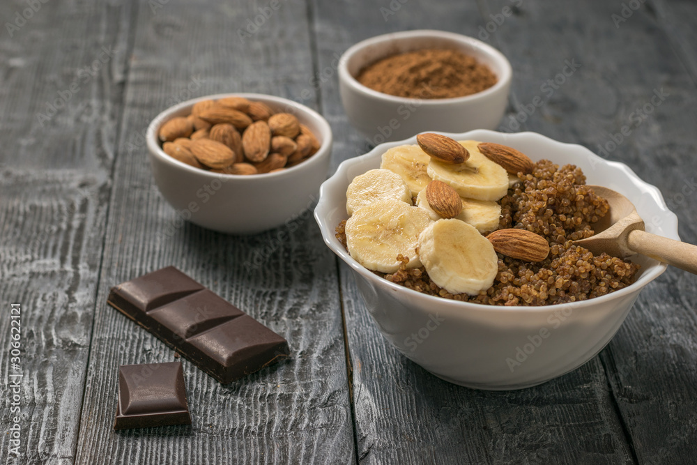 Chocolate chips and quinoa porridge with banana and almonds on a rustic table. Chocolate chips and quinoa porridge with banana and almonds on a rustic table.