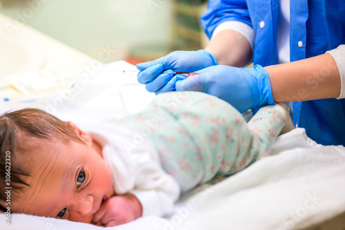 Newborn blood test. The doctor takes blood for examination from the newborn.