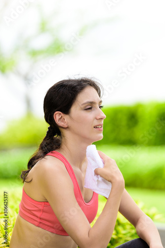 Beautiful woman runner has used a white towel wipe her face after running in the garden.