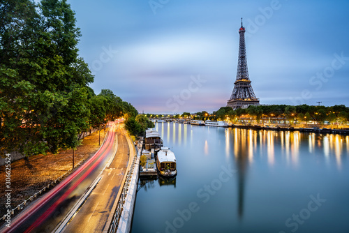 Fototapeta Paris cityscape taken at dawn with the Eiffel tower and the boats reflected on t