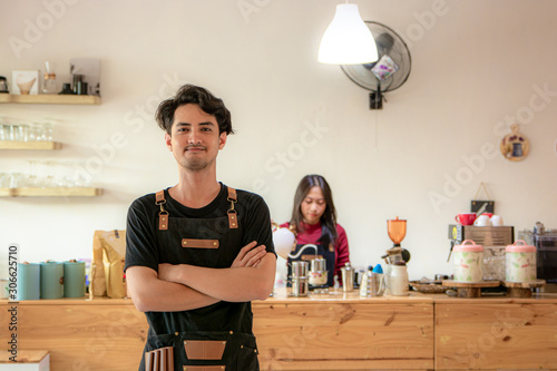 Portrait of a smiling young Asian male entrepreneur standing with her arms crossed