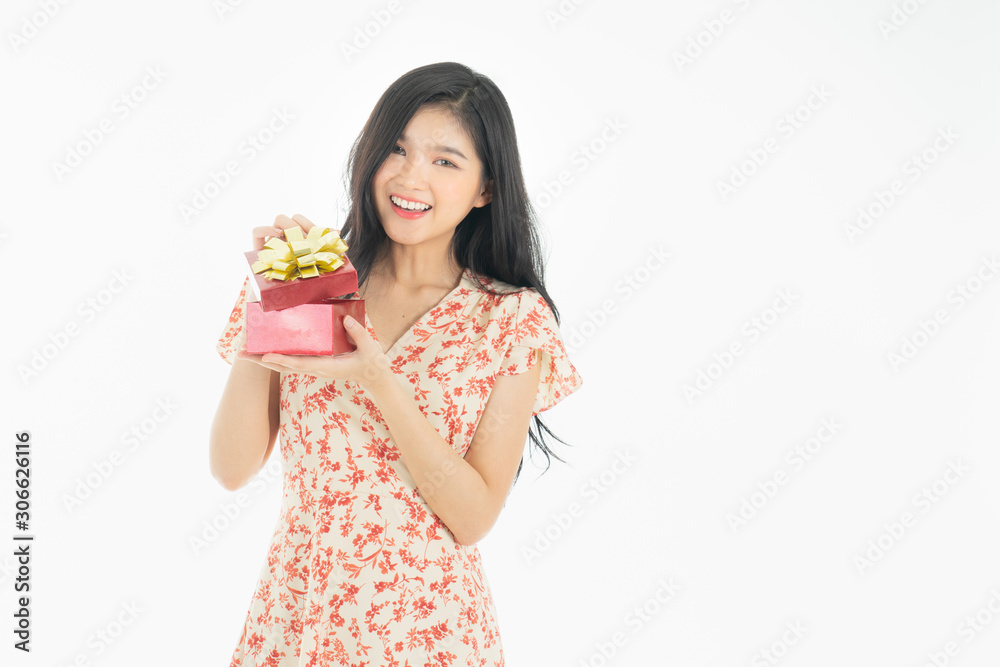 Photo of asian curious woman in red dress rejoicing her birthday or new year gift box. Young woman holding gift box with red bow being excited and surprised holiday. Photo of asian curious woman in red dress rejoicing her birthday or new year gift box. Young woman holding gift box with red bow being excited and surprised holiday.