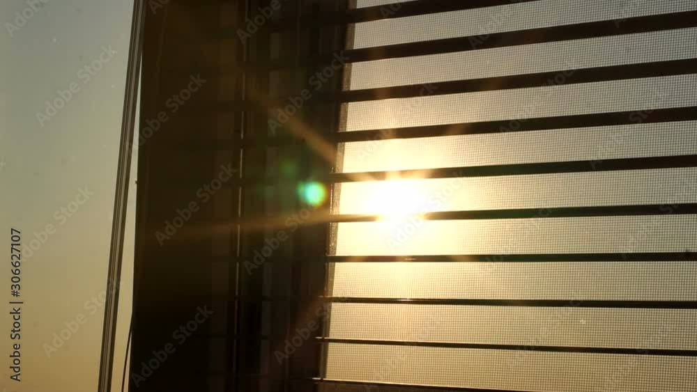 Sunrise behind the window blinds and mosquito net. Rising sun behind window blinds. Sunlight behind vertical blinds. Sunrise behind the window blinds and mosquito net. Rising sun behind window blinds. Sunlight behind vertical blinds.