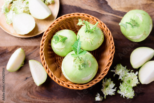 Fresh kohlrabi in basket on wooden background, top view