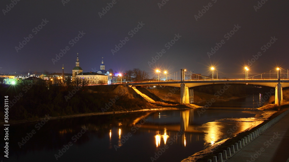 Fototapeta premium Russia, Smolensk famous landmark Uspensky Bridge across Dnieper river with reflection street lights, embankment Park and Church, beautiful wide autumn night view from City Observation deck